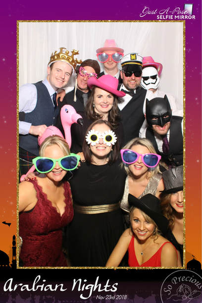 12 people having fun using dress up props in front of selfie mirror photo booth