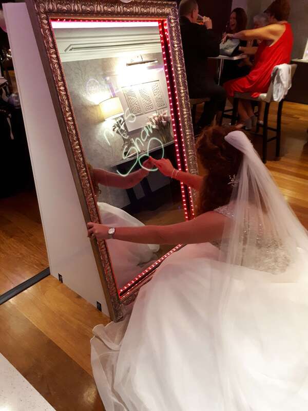 Bride writing her newly married name on the selfie mirror screen