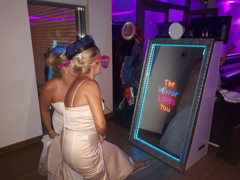 "The Mirror Loves You" animation on the selfie mirror with two bridesmaids having picture taken.